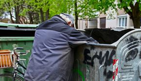 Armut - Das Bild zeigt einen in einer Mülltonne suchenden Mann